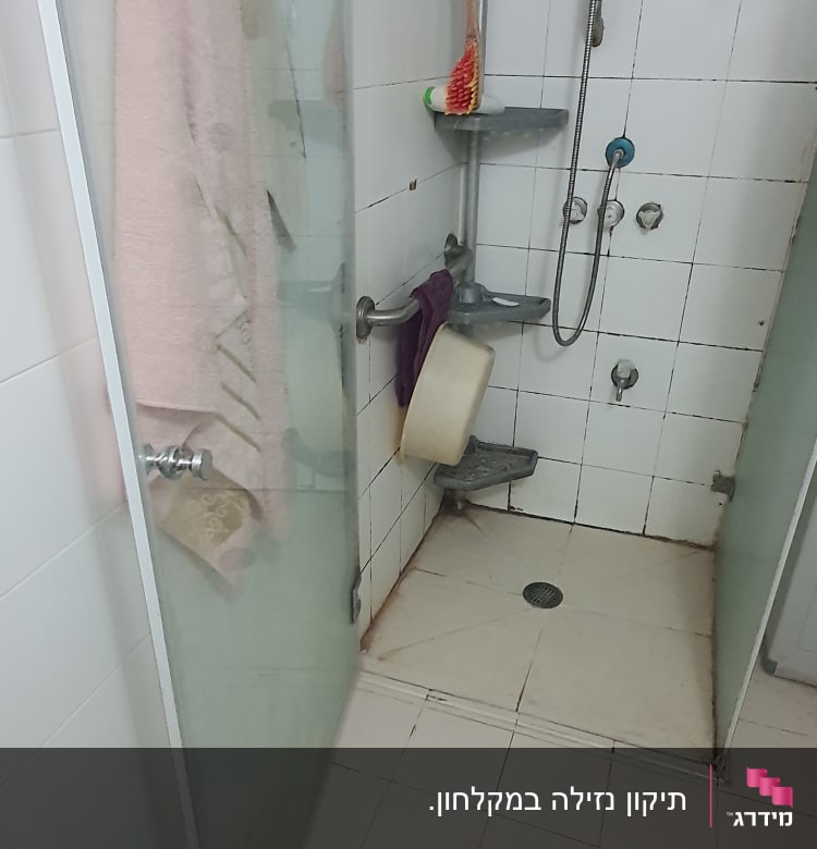 מקלחת עם מדפים, בקבוקי שמפו ומגבת תלויה